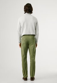 Light gray sweater, green pants with two back pockets and a smooth texture, worn with brown shoes. Minimalistic design, solid colors.