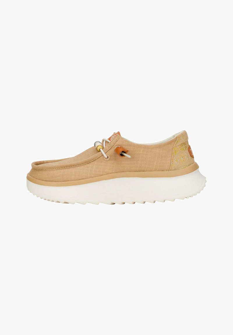 Scarpa slip-on in tela beige con superficie texturizzata, suola in gomma bianca e un sistema di lacci elastici. Presenta un logo discreto sul tallone.