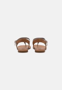 Brown leather sandals with a flat sole, featuring two adjustable straps with a metallic buckle and simple stitching details.