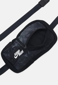 Zwarte netten pouch met een rits en het "JUMP MAN" logo. Beschikt over een gladde stof en een verstelbare band voor een veilige pasvorm.