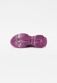 Lila sneaker talp, texturált gumival, jellegzetes cikk-cakk mintázattal, sima, fényes felülettel a középtalpon, lekerekített sarokkal és szellőző elemekkel.