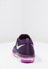 Violetti neulottu urheilukenkä, jossa on valkoinen Nike-logo. Kengässä on teksturoitu päällinen, pehmustettu pohja ja värikäs kuviollinen yksityiskohta kantapäässä.