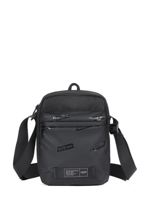 Black crossbody bag made of durable material, featuring a textured front panel with embossed logos, adjustable strap, and zippered compartments.