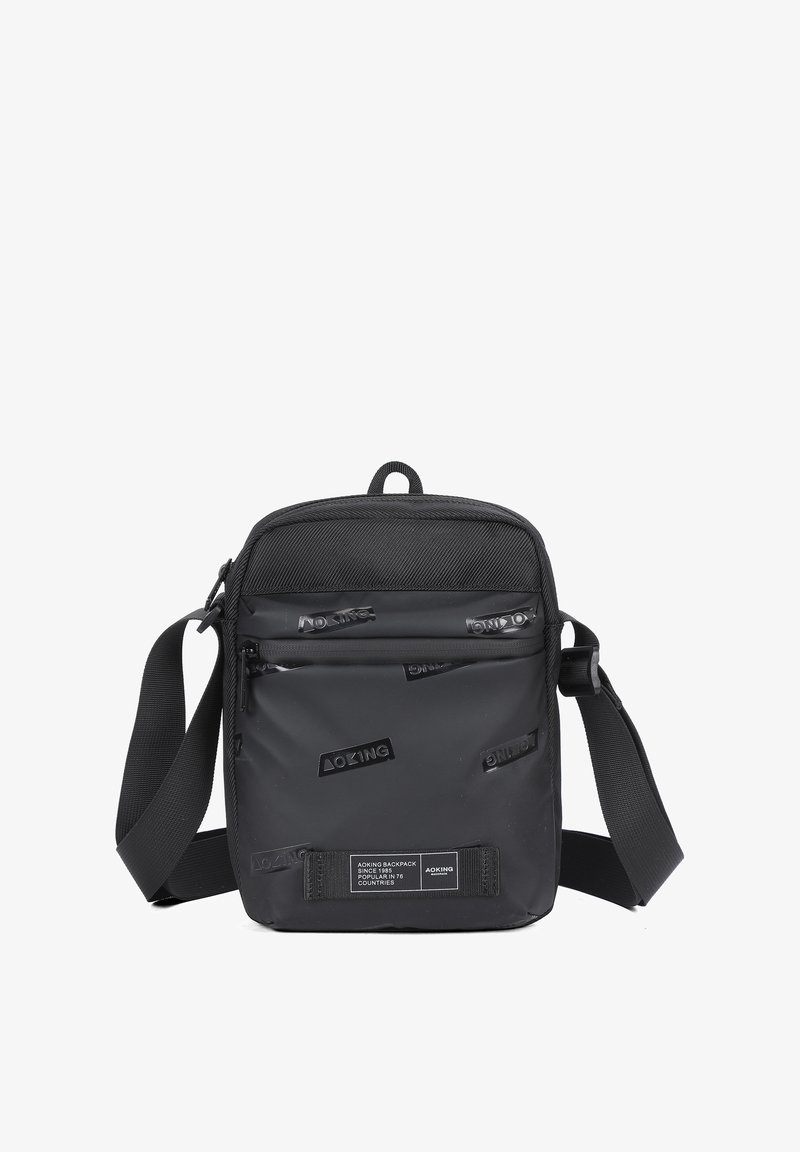 Borsa a tracolla nera realizzata in materiale resistente, con un pannello frontale testurizzato e loghi in rilievo, tracolla regolabile e scomparti con zip.