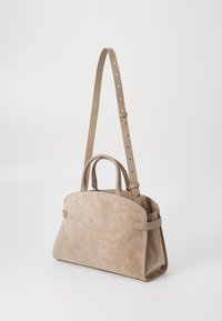 Sac à main en daim beige avec une forme structurée, deux poignées supérieures et une bandoulière amovible et réglable. Présente une couture minimale et des accents en matériel.
