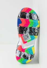 Wielokolorowa podeszwa sportowego buta z teksturowanymi wzorami w kolorach różowym, niebieskim, zielonym i czarnym. Posiada kod QR i etykietę rozmiaru.