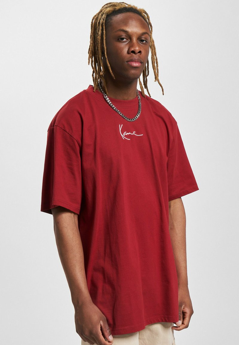 Bordeaux oversized t-shirt i bomuld med korte ærmer, der har et hvidt skriftlogo på brystet og en afslappet pasform.