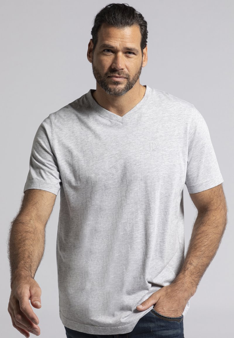 Camiseta de cuello en V de manga corta en gris claro con una textura suave, que presenta un logo sutil en el pecho y un corte relajado, combinada con jeans oscuros.