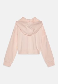 Lyhyt huppari pehmeästä vaaleanpunaisesta kankaasta, jossa on nyörihuppu, pitkät hihat ja ribbaus hihansuissa, sekä pieni logo yksityiskohtana sivulla.