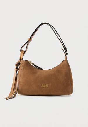 Barna velúr Tommy Hilfiger kézitáska állítható fekete és barna pánttal, valamint bojtos díszítéssel fehér háttéren.