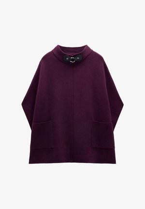 Fioletowy, oversize'owy płaszcz z miękkiej wełny, z wysokim kołnierzem, dwoma przednimi kieszeniami i czarnym zapięciem. Gładka struktura i nowoczesny design.