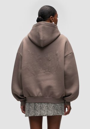 Bruine oversized hoodie met een textuurstikselontwerp op de achterkant, voorzien van een trekkoordcapuchon en geribde manchetten.