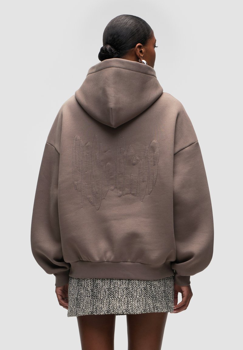 Brown oversized hoodie featuring a textured stitch design on the back, with a drawstring hood and ribbed cuffs.