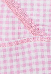 Różowa i biała kratka gingham z teksturowanym, falbanastym różowym wykończeniem na krawędzi, z subtelnymi różnicami w wzorze kratki.