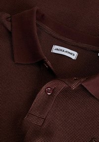Polo marron texturé avec un col et des boutons marron foncé, affichant une étiquette blanche de la marque Jack & Jones à l’intérieur du col.