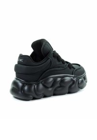 Czarne sneakersy o smukłym designie, z wyprofilowaną, falistą podeszwą, teksturowanym cholewką i czarnymi sznurowadłami; minimalne logo na pięcie.
