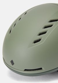 Casco da bicicletta verde oliva opaco con design aerodinamico, fessure di ventilazione e un dettaglio del logo nero sul retro. Texture liscia.