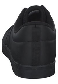 Zapatillas deportivas negras con un acabado mate y suave, que cuentan con una lengüeta trasera, un forro texturizado y una suela de goma.