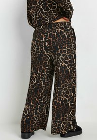 Svarta och bruna leopardmönstrade vida byxor med resårmidja, som har en texturerad tyg och sidofickor. Slät avslutning i nederkant.