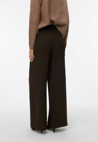 Pantalon marron à jambes larges avec une taille élastique et une finition texturée, assorti à un pull coordonné. Vue de dos montrant une coupe décontractée et fluide.