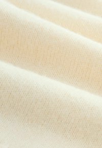 Textured cream fabric with a ribbed pattern, showcasing a soft, fine knit and a smooth, even surface. Minimal variations in tone.