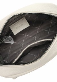 Interno di una borsa in pelle bianca con texture, foderato in grigio, caratterizzato da un motivo a diamante e un piccolo etichetta del marchio. Chiusura con zip e texture morbida.