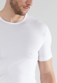 White short-sleeve T-shirt featuring a round neck, smooth texture, and fitted design, with contrasting collar and sleeve accents.