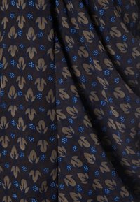 Tejido oscuro con un patrón floral que presenta hojas beige y acentos de puntos azules, creando una apariencia texturizada y en capas.