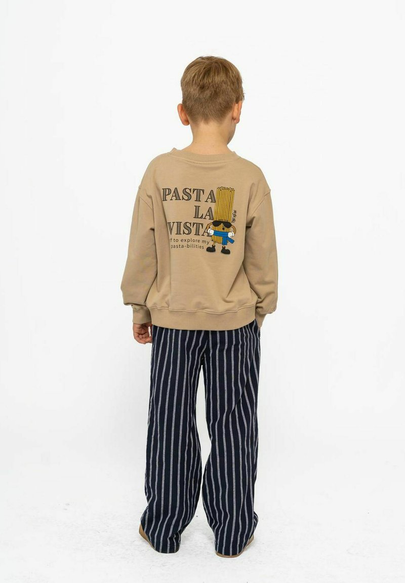 Beige sweatshirt met de tekst "PASTA LA VISTA" en een cartoonfiguur. Gecombineerd met gestreepte marineblauwe en witte wijde broek.