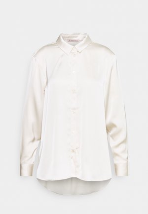 Blouse blanche en satin à manches longues, avec boutons sur le devant, col pointu et ourlet légèrement incurvé, présentée sur un fond clair uni.