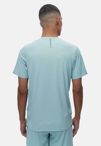 Svetlo modra majica s kratkimi rokavi z teksturirano tkanino in odsevnimi detajli na zgornjem delu hrbta. Zasnova je sproščena in udobna.