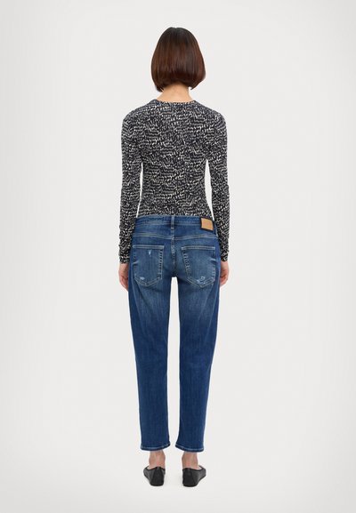 Jeans din denim albastru cu o croială lejeră, având o spălare deschisă, detalii uzate și o etichetă pătrată din piele maro pe talie.