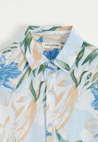 Chemise à manches courtes bleu clair avec un motif floral dans des nuances de bleu, vert et beige, dotée d'un col classique et d'une texture douce.