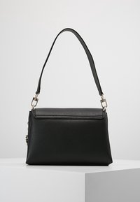 Mustan nahkainen käsilaukku, jossa on rakenteellinen suorakulmainen muoto, lyhyt olkahihna, sileä pinta ja metalliset yksityiskohdat.