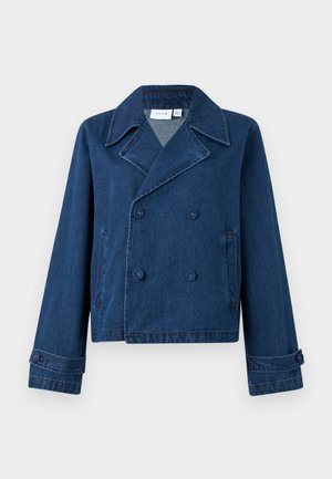 Veste en denim bleu foncé à double boutonnage avec larges revers, poignets boutonnés et poches fendues de chaque côté, présentée sur un fond uni.