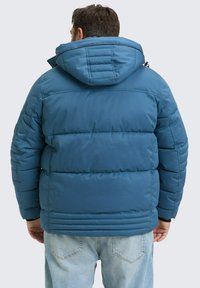 Modra podložena jakna s kapuco, ki ima kviltan dizajn in elastične manšete. Hrbtna stran ima vodoravno šivanje in gladko teksturo.