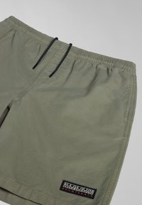 Shorts vert olive clair avec taille élastique, cordons de serrage noirs, poches latérales et un patch logo rectangulaire noir "Napapijri geographic" près de l'ourlet.