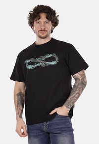 T-shirt nera in cotone con maniche corte, caratterizzata da un elemento di design infinito in turchese stampato sulla parte anteriore. Stile classico con scollo rotondo.