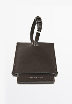 Bruine leren bagagelabel met een gladde textuur, gestikte randen en een verstelbare riem met een metalen gesp.