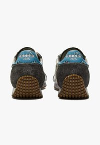 Sneakers retrò grigie e nere con accenti blu, materiali in suede e tessuto, suole strutturate e logo ricamato sul tallone.