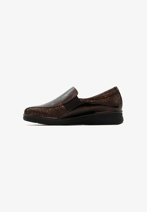 Zapato marrón tipo slip-on con parte superior de cuero brillante, panel texturizado y elástico. Presenta punta redondeada y una suela baja de cuña para mayor soporte.