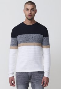 Suéter con cuello redondo, textura acanalada y rayas horizontales en navy, gris, beige y blanco. Tela suave de diferentes puntos de tejido.