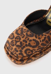 Brune leopardmønstrete platåsko laget av semsket skinn med rund tå og utskårne sider, med svart innvendig og gull detaljer.