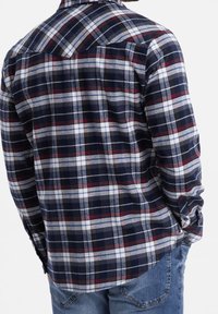 Granatowa koszula flanelowa w kratę z czerwonymi i białymi akcentami, z mankietami na guziki oraz fasonem w stylu zachodnim. Miękka, teksturowana tkanina.