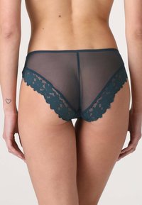 Slip hipster in rete color teal con bordo in pizzo arricciato, caratterizzato da un motivo floreale e materiale trasparente, che mette in risalto un design classico e femminile.