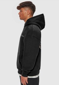 Black hoodie with a front pocket, drawstring hood, and embroidered logo on the chest. Features ribbed cuffs and hem for a snug fit.