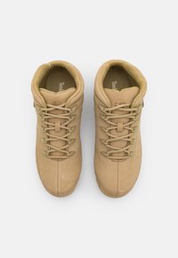 Botas de senderismo de cuero marrón con puntas redondeadas, superficie texturizada, ojales reforzados y cordones a juego. Cuello acolchado para mayor comodidad.
