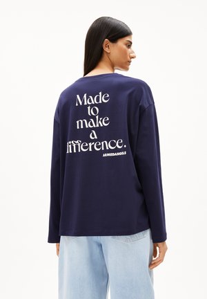 Marineblaue Langarmbluse mit weißem Text "Designed to make a difference." auf dem Rücken. Weicher Stoff, lockere Passform und Rundhalsausschnitt.