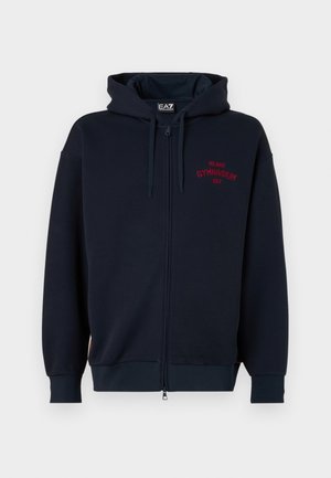 Navy zip-up hoodie with a spacious hood, elastic cuffs, and waistband. Features red text "MILANO GYMNASIUM EA7" on the chest. Soft fabric texture.