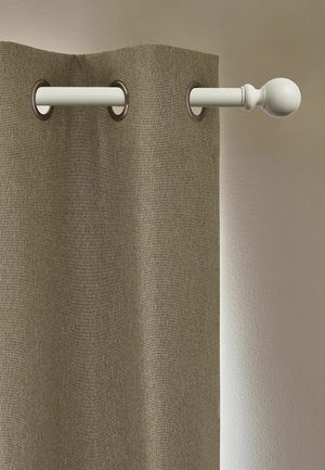 Tenda beige appesa a una barra per tende bianca con terminali rotondi, montata su una parete chiara.